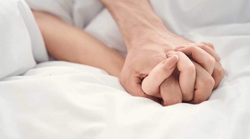 Couple holding hands in bed making love