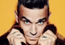 Robbie williams Роби Вилијамс жолта позадина облечен во бунда фаца тетоважи на раце