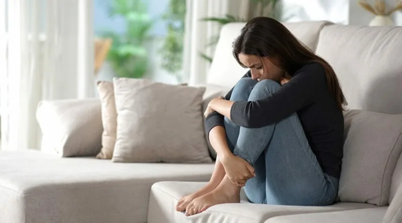 Zamislena devojka sedi doma sofa